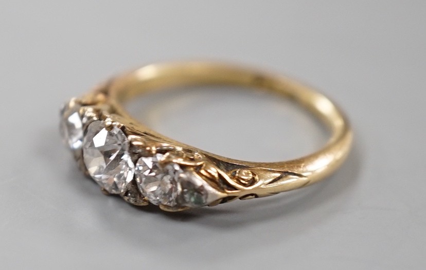 An early 20th century yellow metal and graduated three stone diamond ring, with diamond chip set shoulders, size J, gross weight 3 grams.